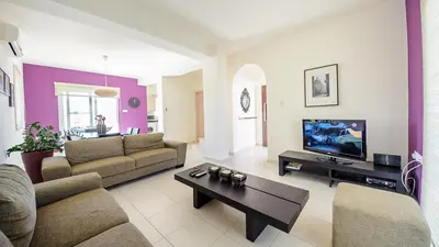 a living room with a couch and a tv at Pernera Holiday Villa 012 in Protaras