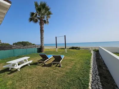 two chairs and a picnic table next to the beach at Ammos Beachfront Villa Paradise in Larnaka