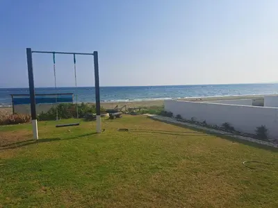 a swing in the grass next to the beach at Ammos Beachfront Villa Paradise in Larnaka