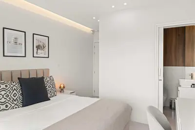 a white bedroom with a bed and a chair at Phaedrus Living: Limassol Seaside Residences 01 in Limassol