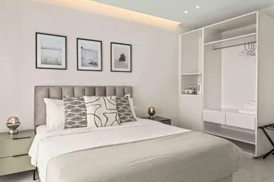 a white bedroom with a bed and some pictures on the wall at Phaedrus Living: Limassol Seaside Residences 02 in Limassol