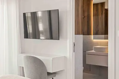 a white bathroom with a sink and a chair at Phaedrus Living Coastal Seaside Residences 04 in Limassol
