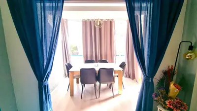 a dining room table with chairs and blue curtains at 2Br Apt Coastal Comfort with Internet Access in Larnaka