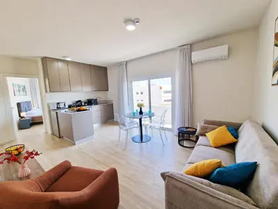 a living room with a couch and a table and a kitchen at Kitieos Central Apartment with Sea View in Larnaka