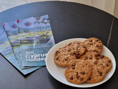 a plate of cookies on a table next to a book at Kitieos Central Apartment with Sea View in Larnaka