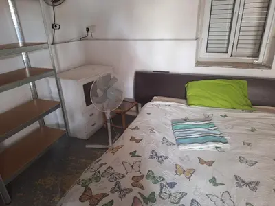a bedroom with a bed with a green pillow and a fan at Room with private entrance from outside, traditional house in Livadhia