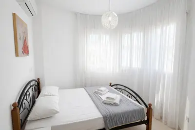 a white bedroom with a bed with white curtains at Villa Dolce Vita in Protaras