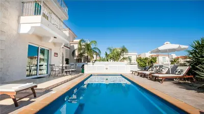 a house with a swimming pool with chairs and an umbrella at Protaras Holiday Villa 045 in Protaras