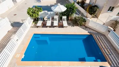 an overhead view of a swimming pool with chairs and an umbrella at Protaras Holiday Villa 045 in Protaras