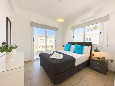 a bedroom with a large bed with blue pillows at Ayia Napa Holiday Villa 040 in Ayia Napa