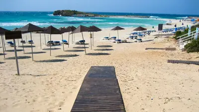 a sandy beach with umbrellas and chairs and the ocean at Ayia Napa Holiday Villa 036 in Ayia Napa