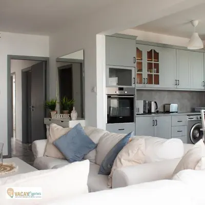 a living room with a white couch and a kitchen at Downtown Larnaca Apartment in Larnaka