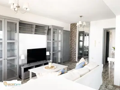a living room with a white couch and a tv at Downtown Larnaca Apartment in Larnaka