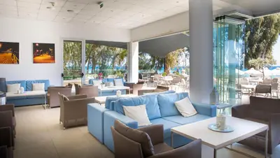 a restaurant with a blue couch and tables and chairs at Harmony Bay Hotel in Limassol