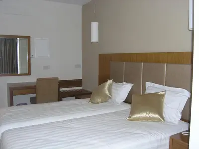 a bedroom with a bed with white sheets and gold pillows at Livadia Hotel Kyperounta in Kyperounda