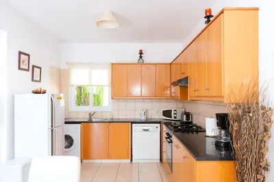 a kitchen with wooden cabinets and a white refrigerator at Villa Cypriana in Protaras