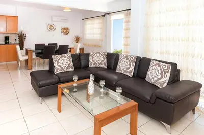 a living room with a black couch and a table at Villa Cypriana in Protaras