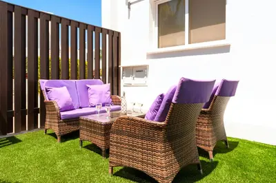 a patio with two chairs and a table with purple cushions at Villa Cypriana in Protaras