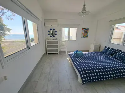 a bedroom with a bed and a view of the ocean at Sandy Coast Beach Villa in Larnaka