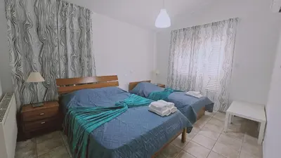 a bedroom with two beds with blue sheets and a window at STAY Princess Villa in Protaras