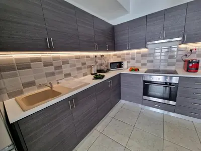 a kitchen with wooden cabinets and a sink and a stove at Tropical Paradise 200m from Finikoudes beach in Larnaka