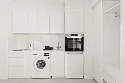 a white kitchen with a washing machine and a microwave at Phaedrus Living: Limassol Seaside Residences 05 in Limassol