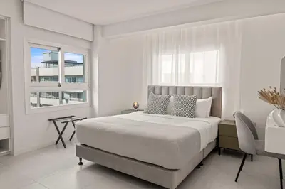 a white bedroom with a large bed and a chair at Phaedrus Living: Limassol Seaside Residences 05 in Limassol