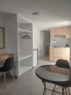 a living room with a table and a kitchen at Green Bay Suites in Protaras