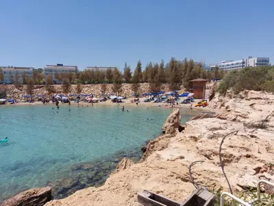 a beach with a bunch of people in the water at Green Bay Suites in Protaras