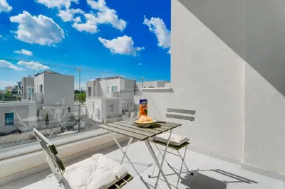 a table and chairs on a balcony with a view of a city at NEW 2BR Townhouse in Luxury Resort Pool & Beach in Protaras