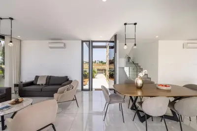 a dining room and living room with a table and chairs at Villa Pliades in Ayia Napa