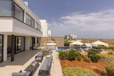 an outdoor patio with lounge chairs and a swimming pool at Villa Pliades in Ayia Napa