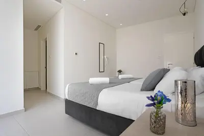 a white bedroom with a bed and a vase of flowers at Villa Sunrise Memory - 150m from Trinity Beach in Protaras