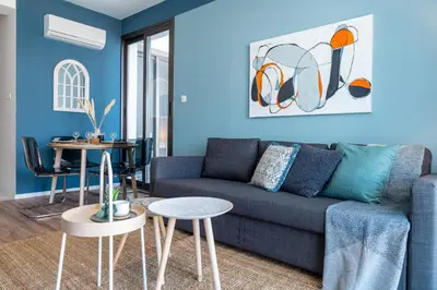 a blue living room with a blue couch and tables at Hue 1-Bedroom Apartment in Larnaca in Larnaka