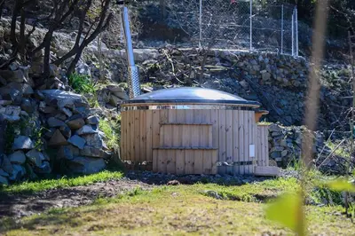 a small wooden building with a tin roof next to a stone wall at Serenity Mountain in Askas