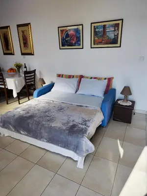 a bedroom with a blue bed and a table at Mariam Apartment in Larnaka