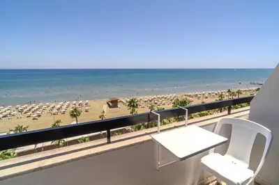 a balcony with a table and chairs and a beach at Finikoudes Seaview Vibe 1 Bdr Flat in Larnaka
