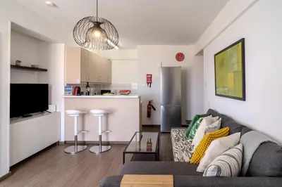 a living room with a couch and a kitchen at Finikoudes Seaview Vibe 1 Bdr Flat in Larnaka
