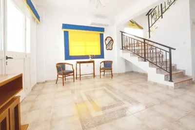 a living room with a table and chairs and stairs at Villa Chloe in Ayia Napa