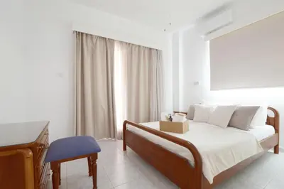 a white bedroom with a bed and a piano at Villa Chloe in Ayia Napa