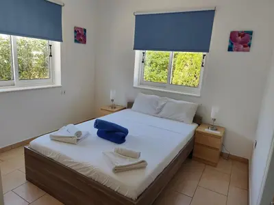 a bedroom with a bed with two towels and two windows at Sunrise Experience in Ayia Napa
