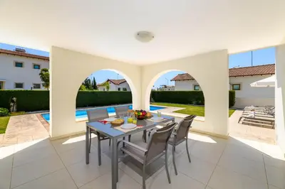 a patio with a table and chairs and a pool at Kymma Bungalow #2 in Ayia Napa