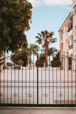 a gate in front of a building with a palm tree at Mercury Apartment in Livadhia
