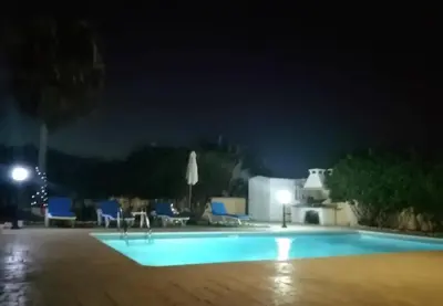 a swimming pool at night with chairs and umbrellas at Villa Elena Gardens in Ayia Napa