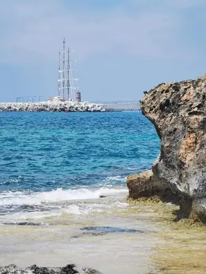 a rock on the beach with a lighthouse in the distance at Villa Elena Gardens in Ayia Napa