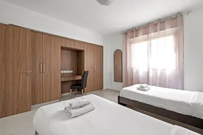 a hotel room with two beds and a desk at Downtown 2 Bedroom Apartment in Larnaka