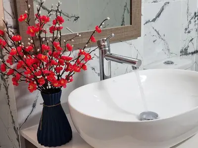 a bathroom with a sink with red flowers in a vase at Parrots Paradise 100m from Finikoudes beachfront in Larnaka