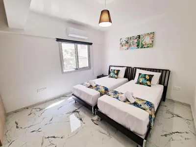 a room with two beds and a window at Parrots Paradise 100m from Finikoudes beachfront in Larnaka
