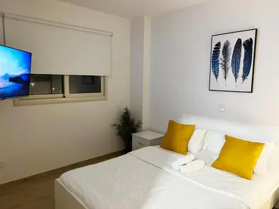 a bedroom with a bed with yellow pillows and a tv at Earth Apartment in Larnaka