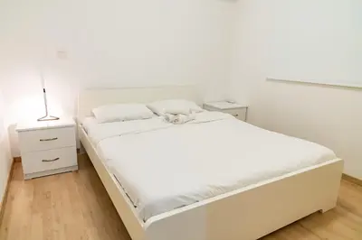 a white bedroom with a white bed and a lamp at Earth Apartment in Larnaka